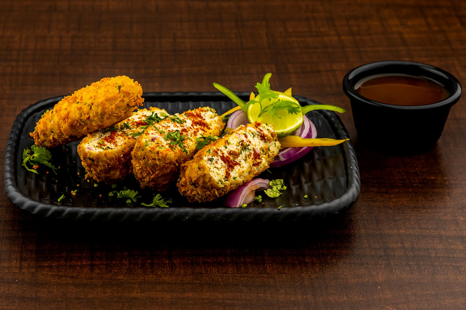 a black plate topped with food next to a cup of coffee
