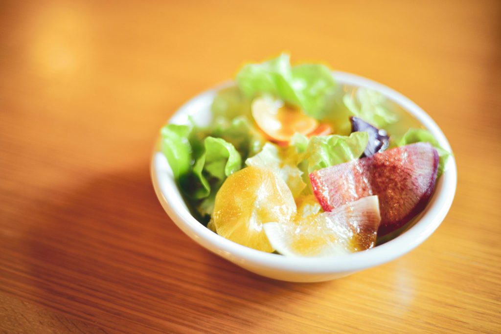 eine weiße Schale mit Obst gefüllt auf einem Holztisch